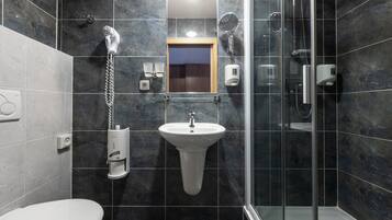 Une salle de bain moderne avec une douche à parois de verre, un lavabo sur colonne et des toilettes.
