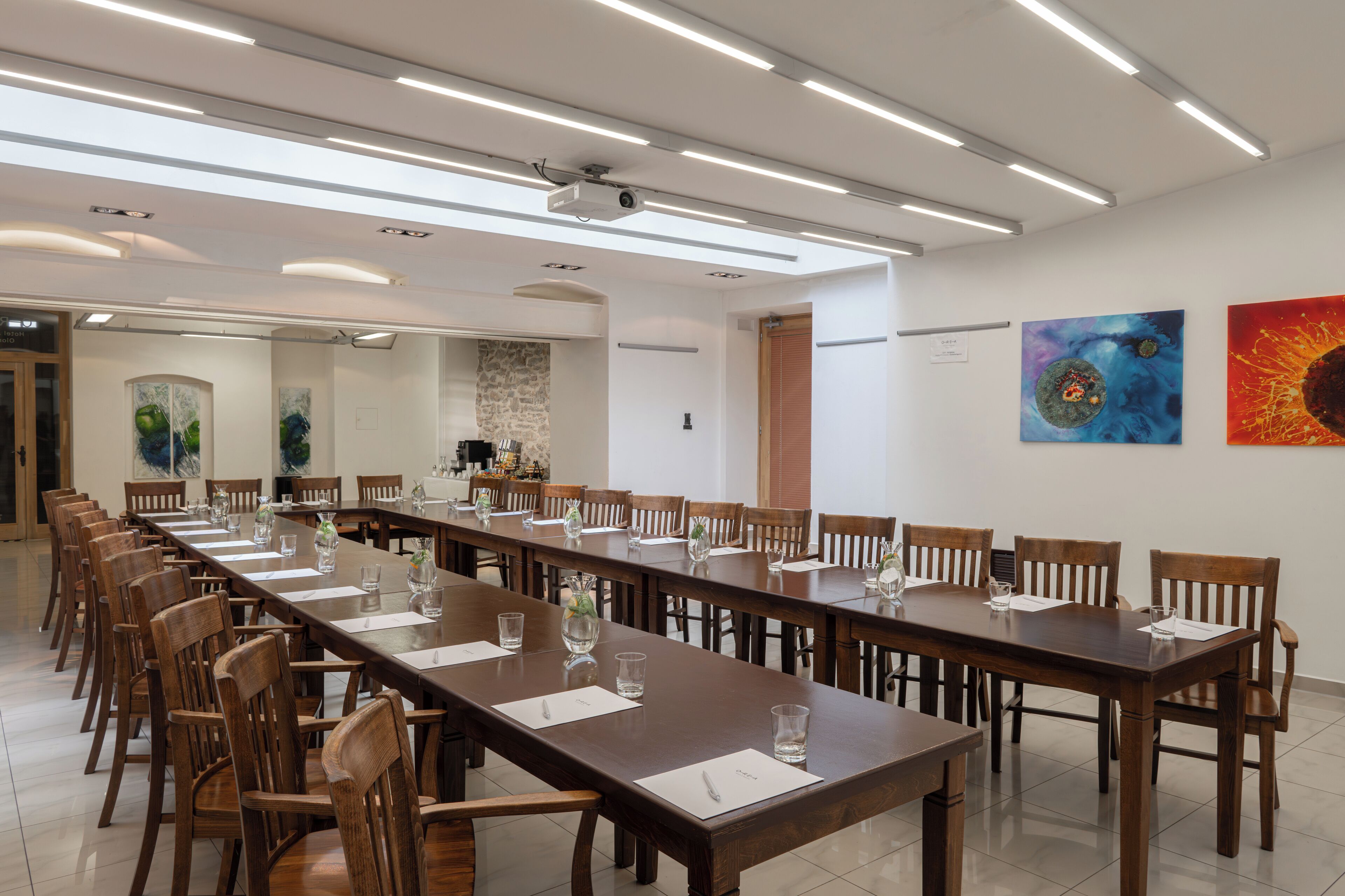 Un salón de conferencias con una larga mesa, sillas y obras de arte en las paredes.