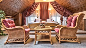 A cozy room with a wooden ceiling, a bed with white linens, and two wicker chairs with red cushions. - OREA Hotel Arigone Olomouc (Olomouc)