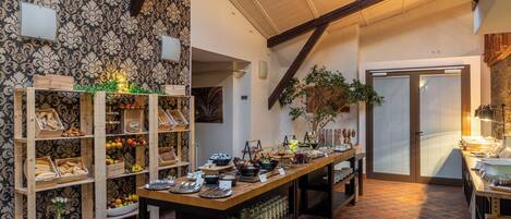 A buffet setup with wooden shelves and a long table, featuring various food items and glassware.