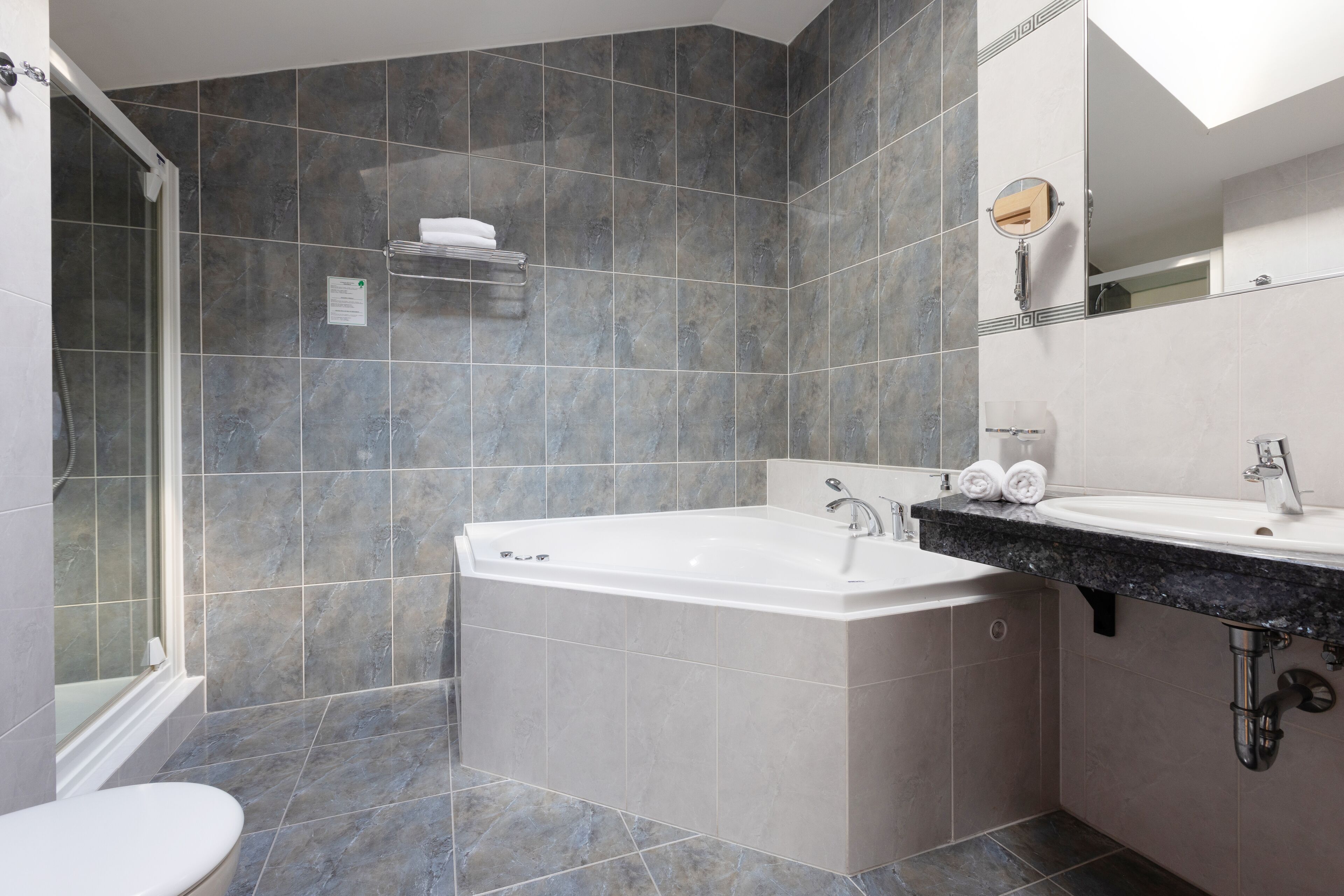 A modern bathroom with a bathtub, a sink, and a shower area.