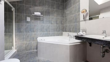 A modern bathroom with a bathtub, a sink, and a shower area.