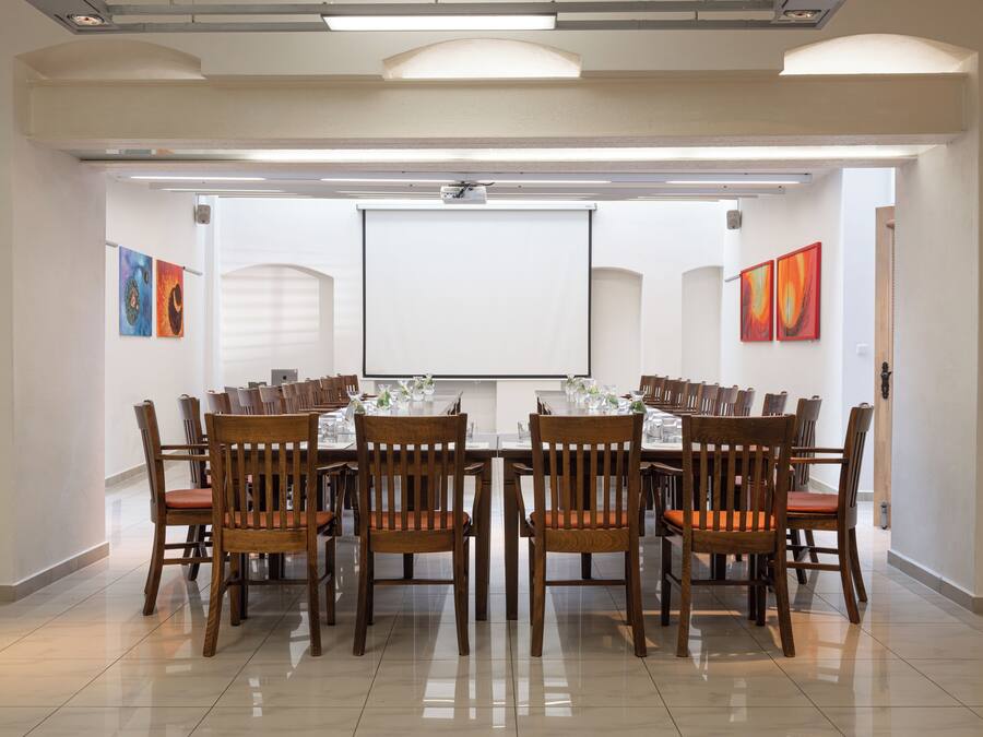 A conference room with a large table, chairs, a projector screen, and artwork on the walls.