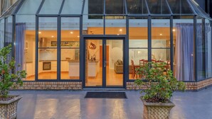Una casa moderna con fachada de vidrio, cocina, comedor y sala de estar.