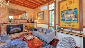 Una habitación acogedora con chimenea, un sofá, una mesa de centro y un cartel grande enmarcados de un caballo.
