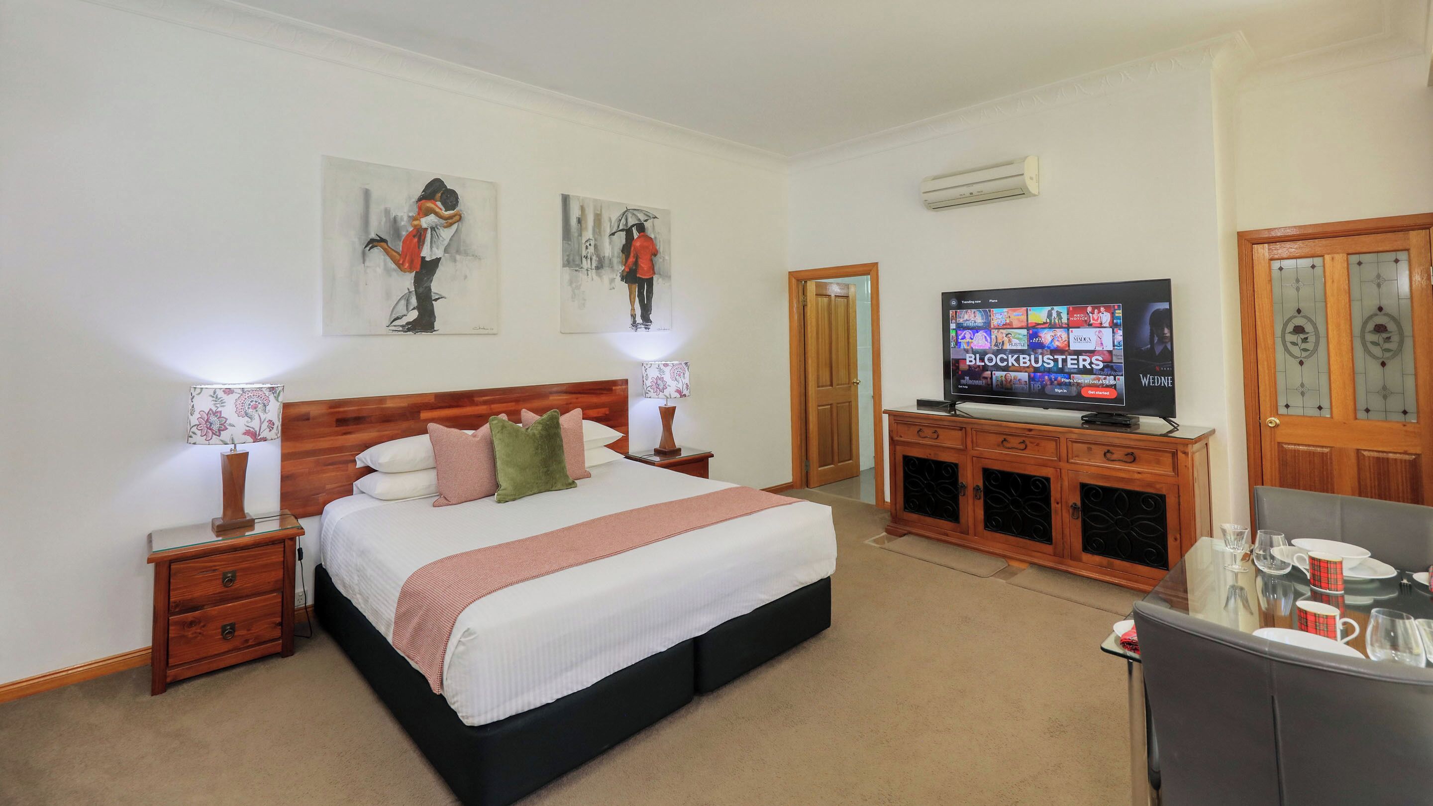 A hotel room with a large bed, a television, and artwork on the walls.