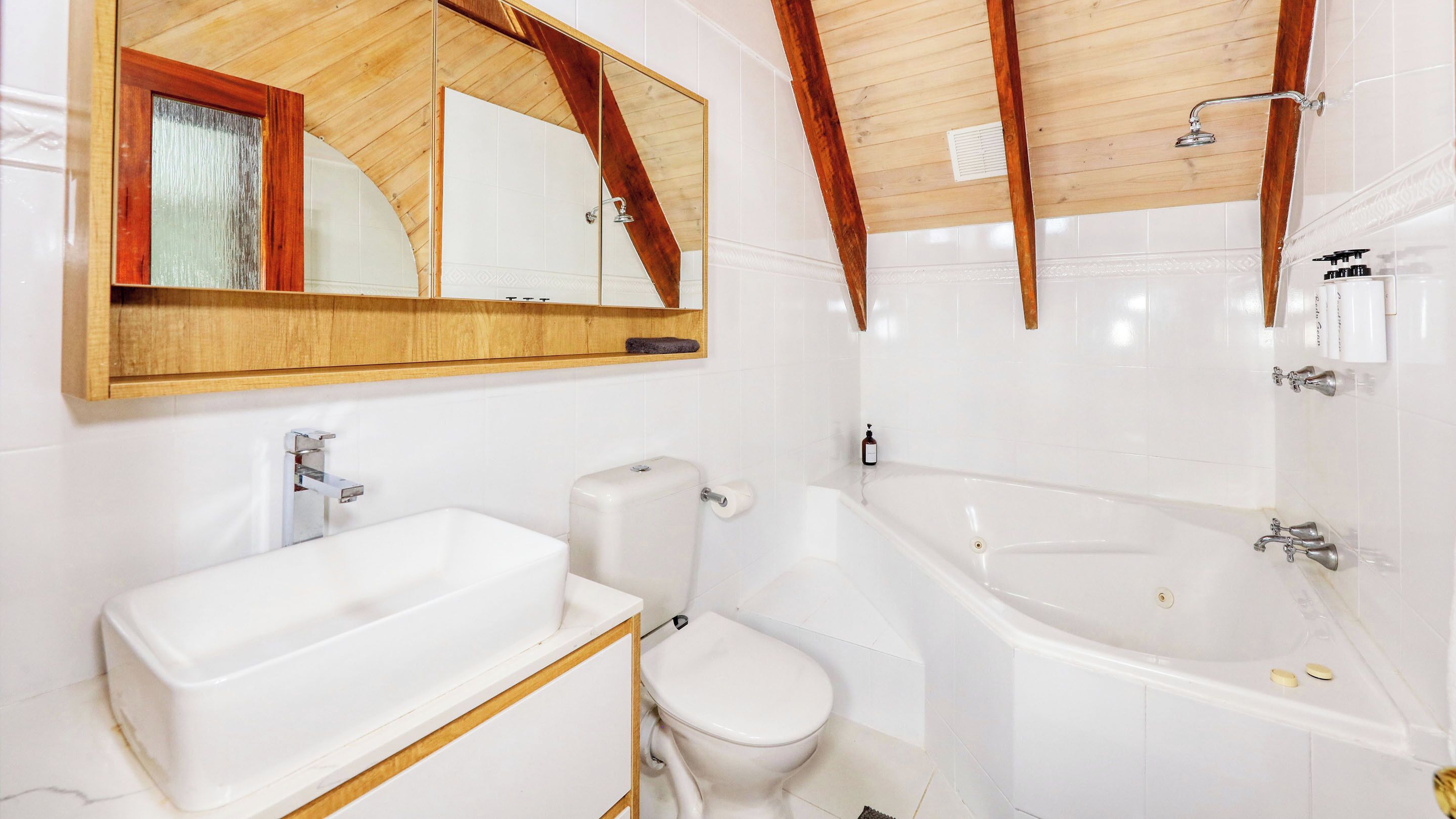 Un bagno moderno con uno specchio grande, un lavandino bianco, un water e una vasca da bagno.
