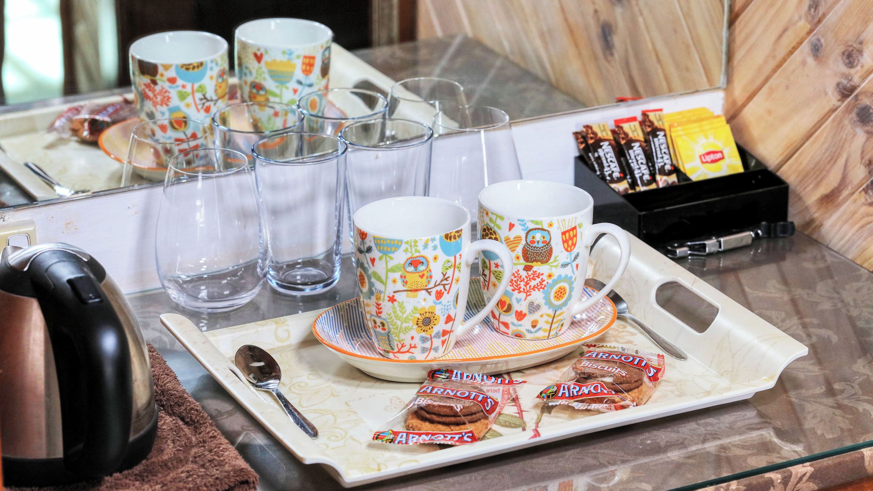 A tray with two mugs, a spoon, and some biscuits on a table.
