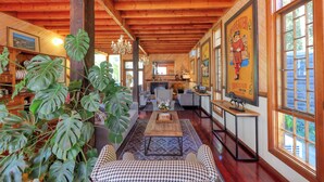 Una habitación acogedora y bien iluminada con vigas de madera, una chimenea y un amplio ventanal con obras de arte.