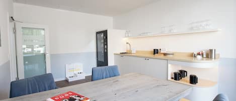 A modern kitchen with a built-in oven, a coffee machine, and a shelf with glasses.