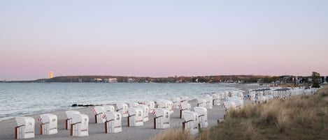 A beach with rows of white mailboxes numbered 1-49, a sandy shore, and a calm sea.