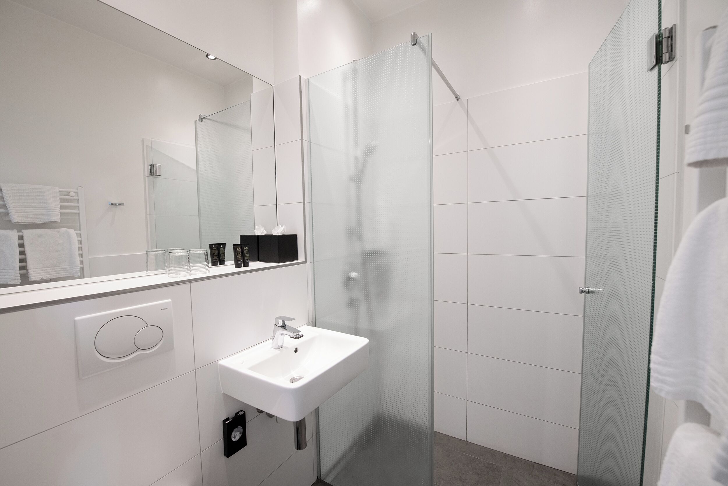 A modern bathroom with a glass-enclosed shower, a white sink, and a large mirror.