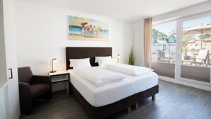 Una habitación de hotel moderna con una cama grande, un escritorio, una silla y un cuadro de una escena de playa.