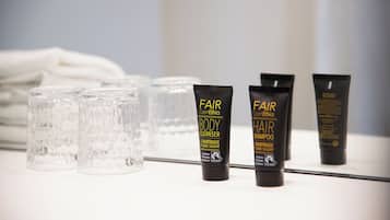 Presentación de productos para el cabello con botellas de vidrio transparente y tubos negros sobre una superficie blanca.