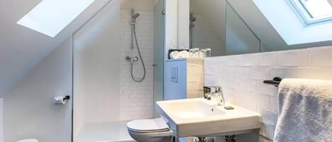 Un baño moderno con tragaluz, ducha, inodoro y lavamanos.