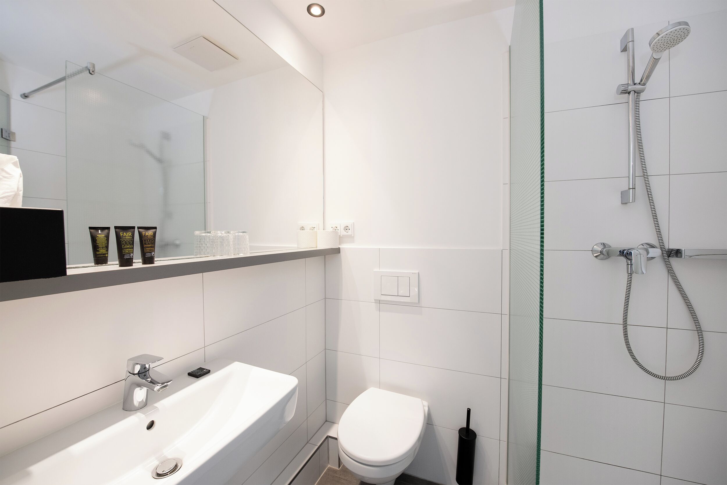 A modern bathroom with a white sink, toilet, and glass-enclosed shower.