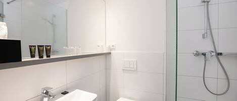 A modern bathroom with a white sink, toilet, and glass-enclosed shower.