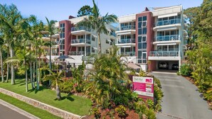 A multi-story hotel with balconies, surrounded by palm trees and a well-maintained lawn. - Bali Hai Apartments Noosa (Noosa Heads)