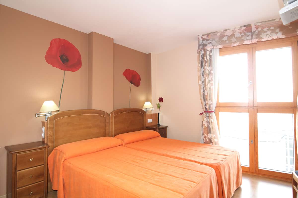 Hotellihuone, jossa on suuri sänky, yöpöytä, lamppu ja ikkuna, josta on näkymä.