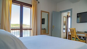 Habitación de hotel con cama, escritorio con silla, televisión y vista al mar.