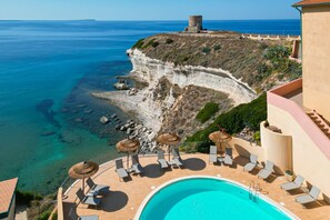 Un resort con piscina, sillones de descanso y vista al mar.