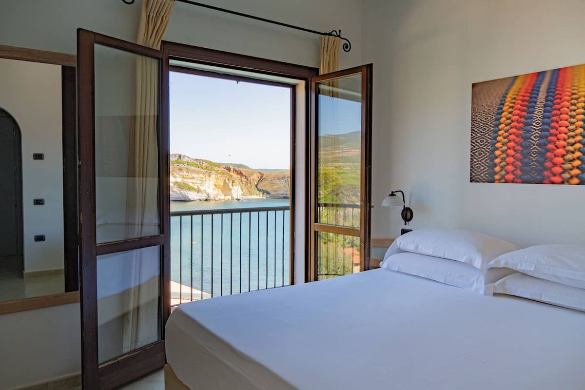 Ein Schlafzimmer mit einem großen Bett, Meerblick und einem Gemälde an der Wand.