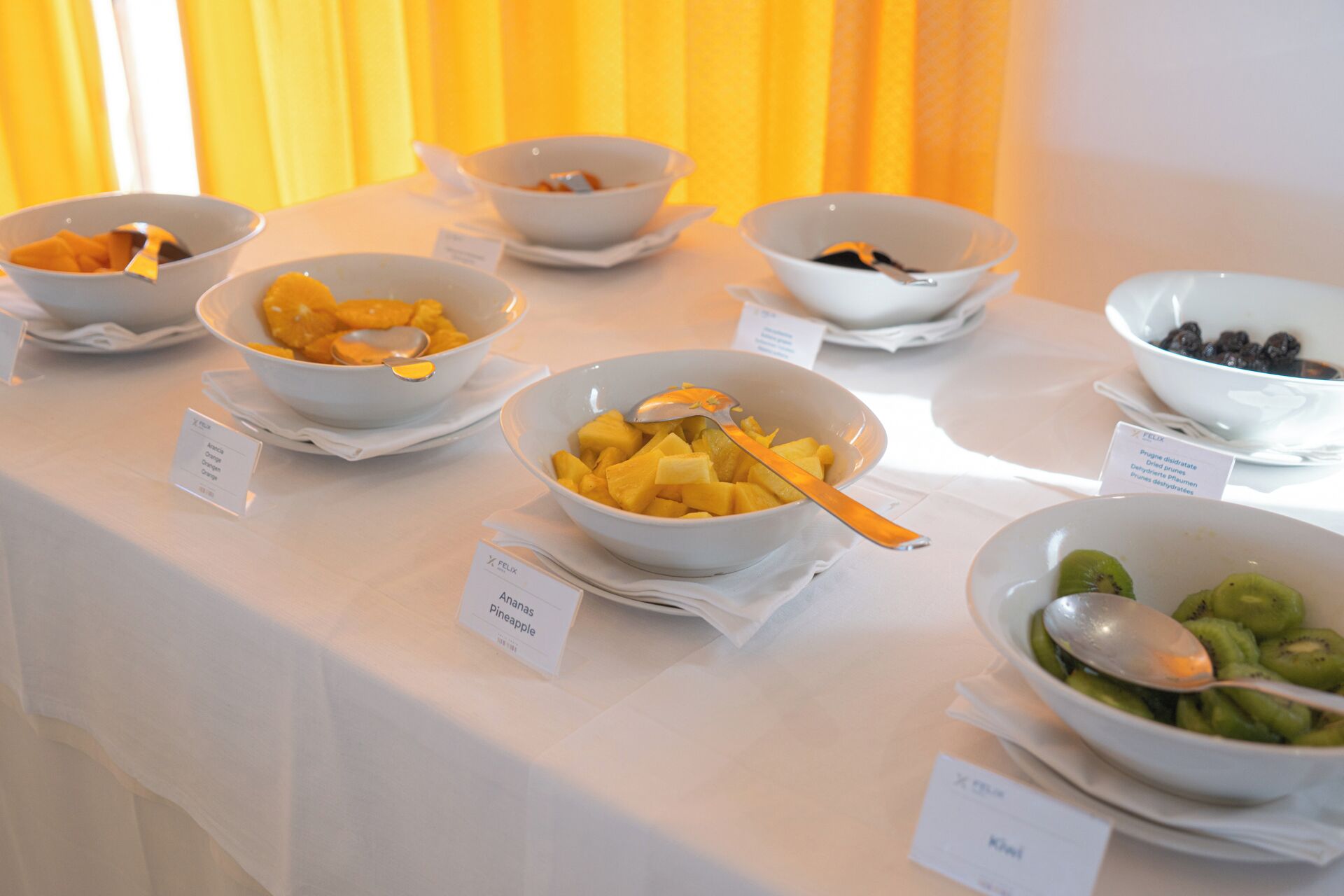 Ein Buffet mit Schalen voller verschiedener Früchte und einem Schild, das die Namen der Früchte angibt.