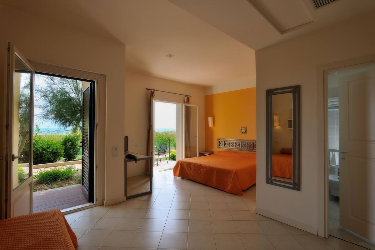 Habitación de hotel con cama, escritorio y baño visible a través de una puerta abierta.