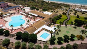 An aerial view of a resort with a large swimming pool, multiple sun loungers, and a beach area. - Zeta Club Sikania Eco Resort (Butera)