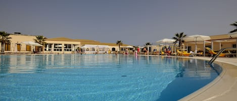 Een buitenzwembad, parasols voor strand/zwembad