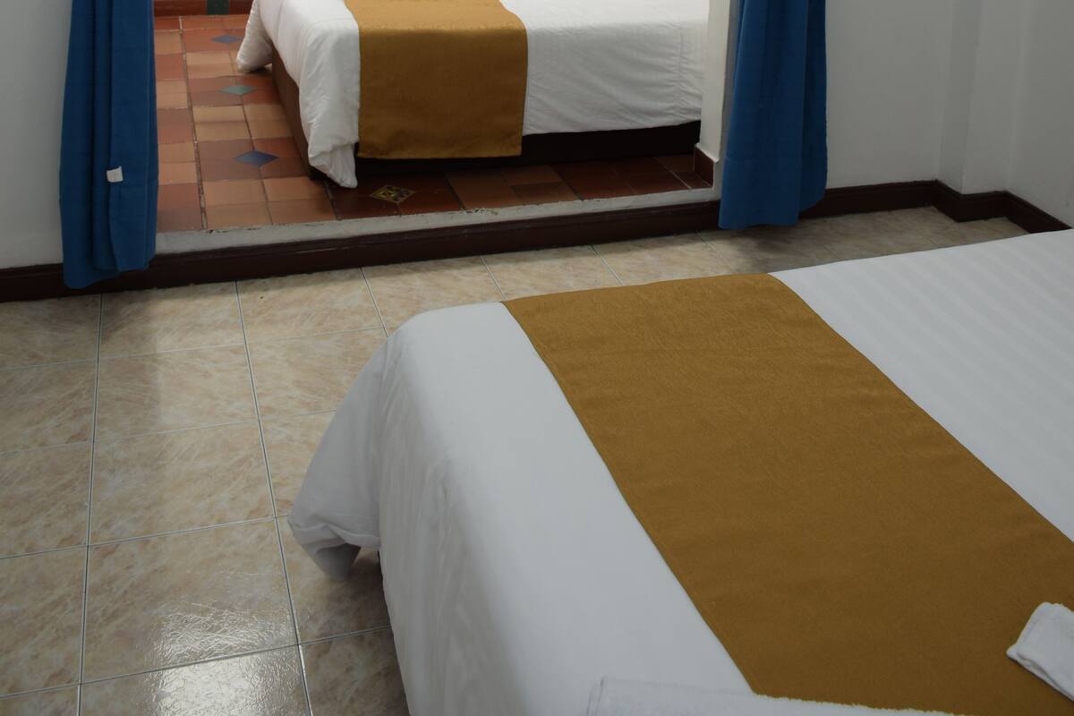 Een hotelkamer met een bed, een bruine plaid en blauwe gordijnen.
