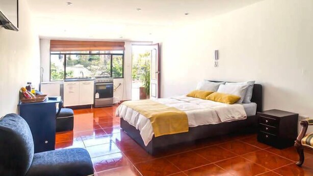 Un dormitorio con cama, escritorio y vista al exterior.