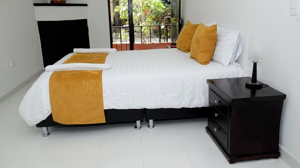 A bedroom with a bed, bedside table, and a view of the outdoors.