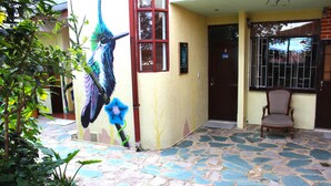 Un edificio con un patio de baldosas de piedra, un mural de un pájaro y una puerta marcada con el número 3.