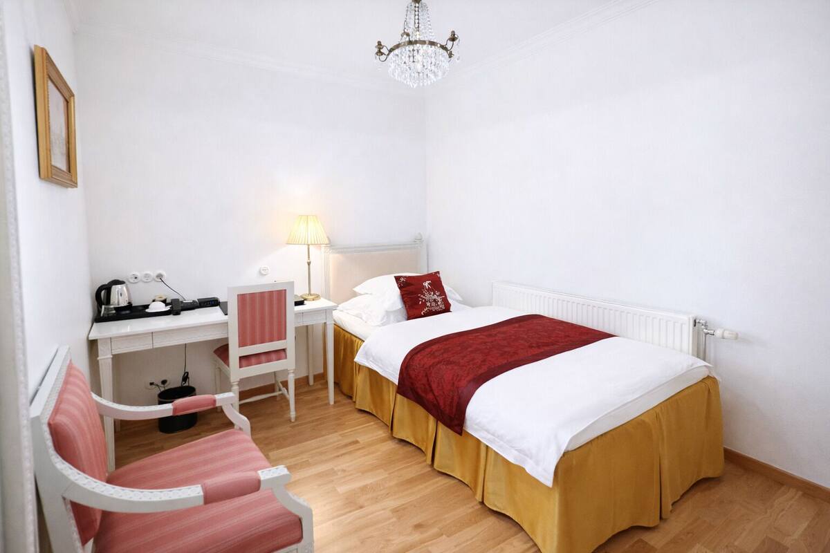 Un dormitorio con cama, escritorio, silla, lámpara y candelabro.