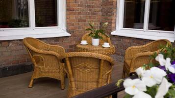 A wicker table with chairs and a potted plant on a wooden deck.