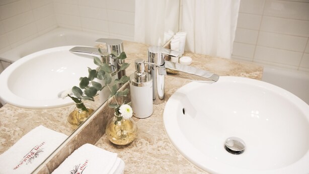 A bathroom with two sinks, a mirror, and a towel rack. - Brommavik Hotel (Bromma)