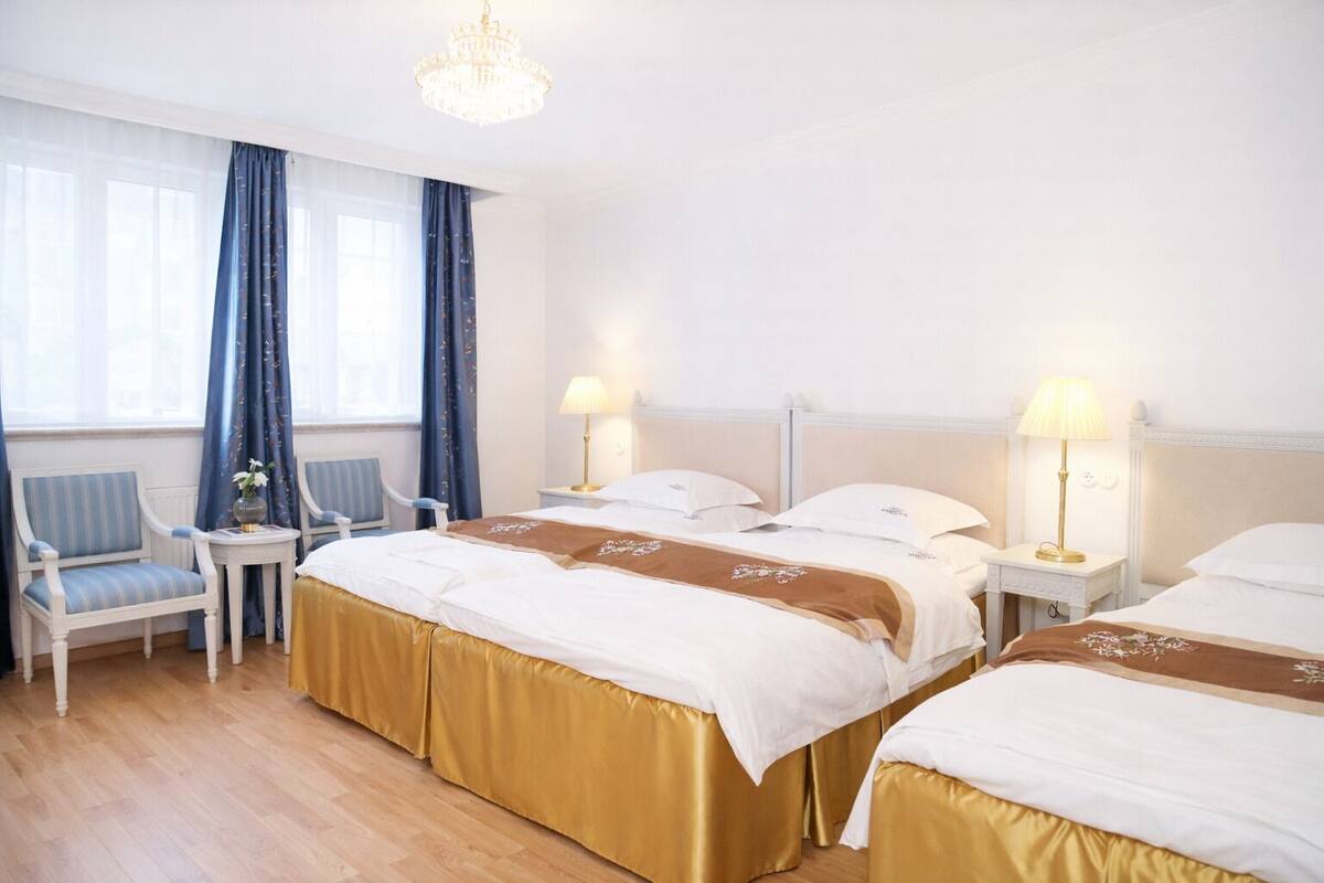 Habitación de hotel con dos camas, una silla, una mesa y un candelabro.