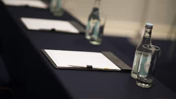 A conference table with documents, pens, and water bottles.