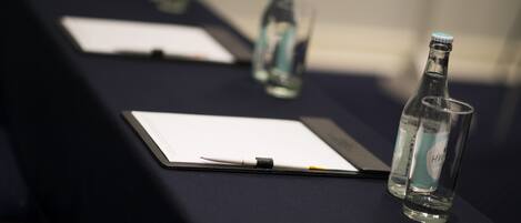 A conference table with documents, pens, and water bottles.