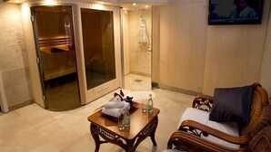 A hotel room with a glass-enclosed shower, a wooden table with toiletries, and a wicker sofa. - Brommavik Hotel (Bromma)