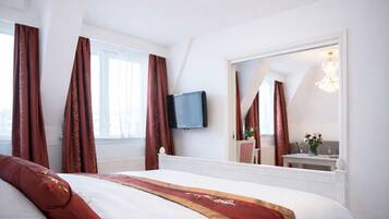 Ein Hotelzimmer mit einem Bett, einem Fernseher, einem großen Spiegel und einer Kandelaber.