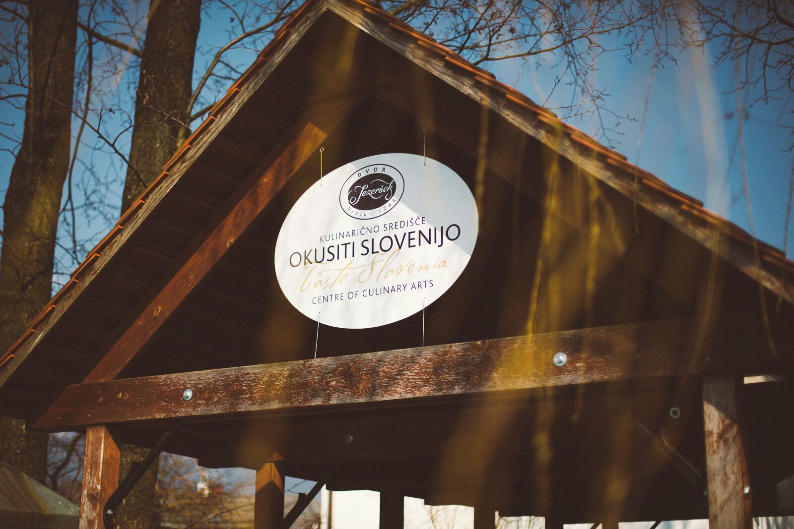 A wooden structure with a sign indicating it is the 'KULINARIČNO SREDIŠČE OKUSITI SLOVENIJO' and 'CULTURAL CENTER OF CULINARY ARTS'.