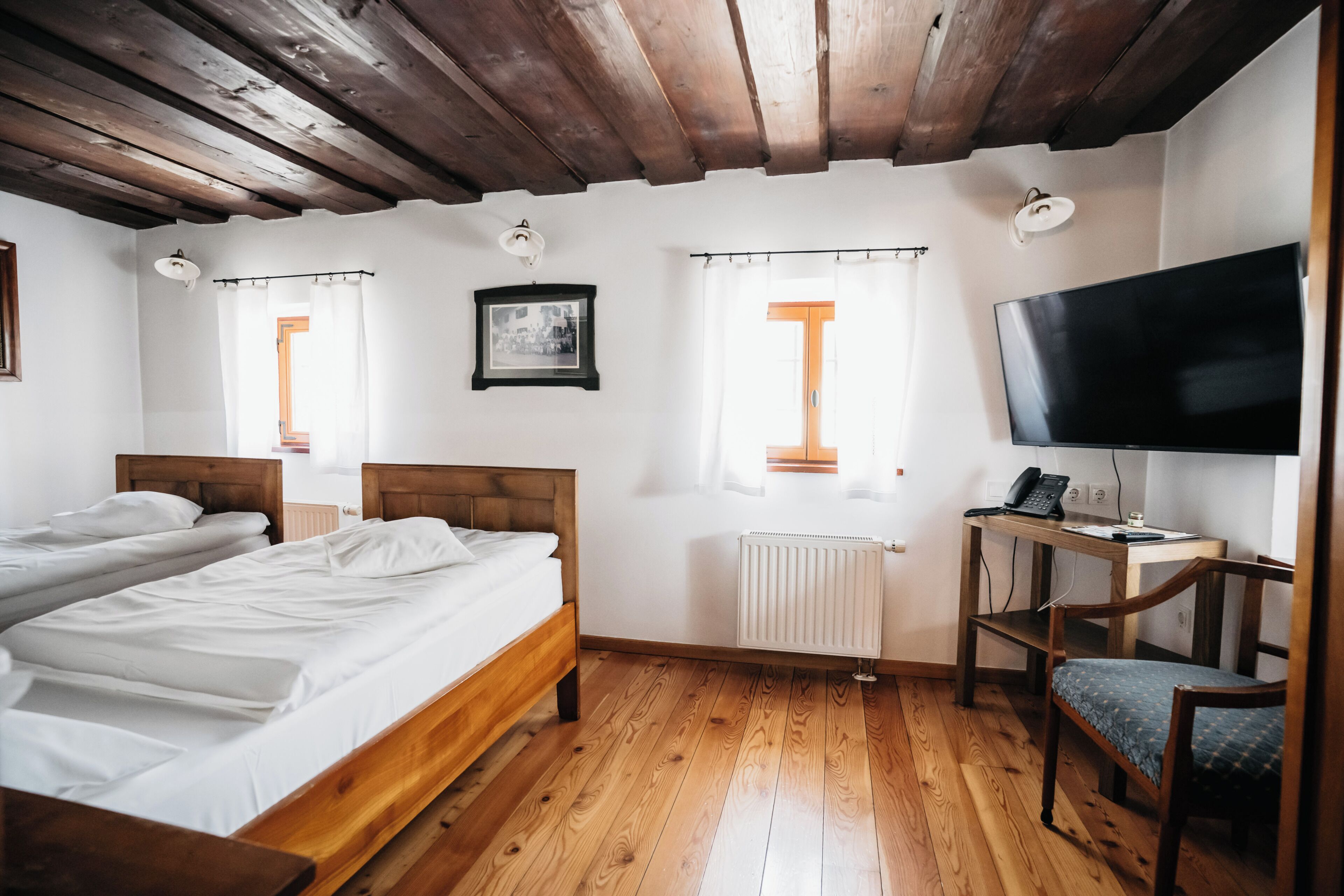 Een kamer met twee bedden, een bureau met een computer, een televisie en een radiator.