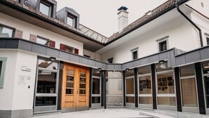 A hotel entrance with a wooden door, glass windows, and a tiled courtyard. - Dvor Jezeršek Brnik (Cerklje na Gorenjskem)