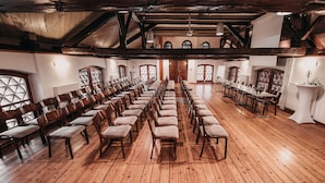 A spacious hall with wooden floors and high ceilings, featuring rows of chairs and tables arranged for events. - Dvor Jezeršek Brnik (Cerklje na Gorenjskem)