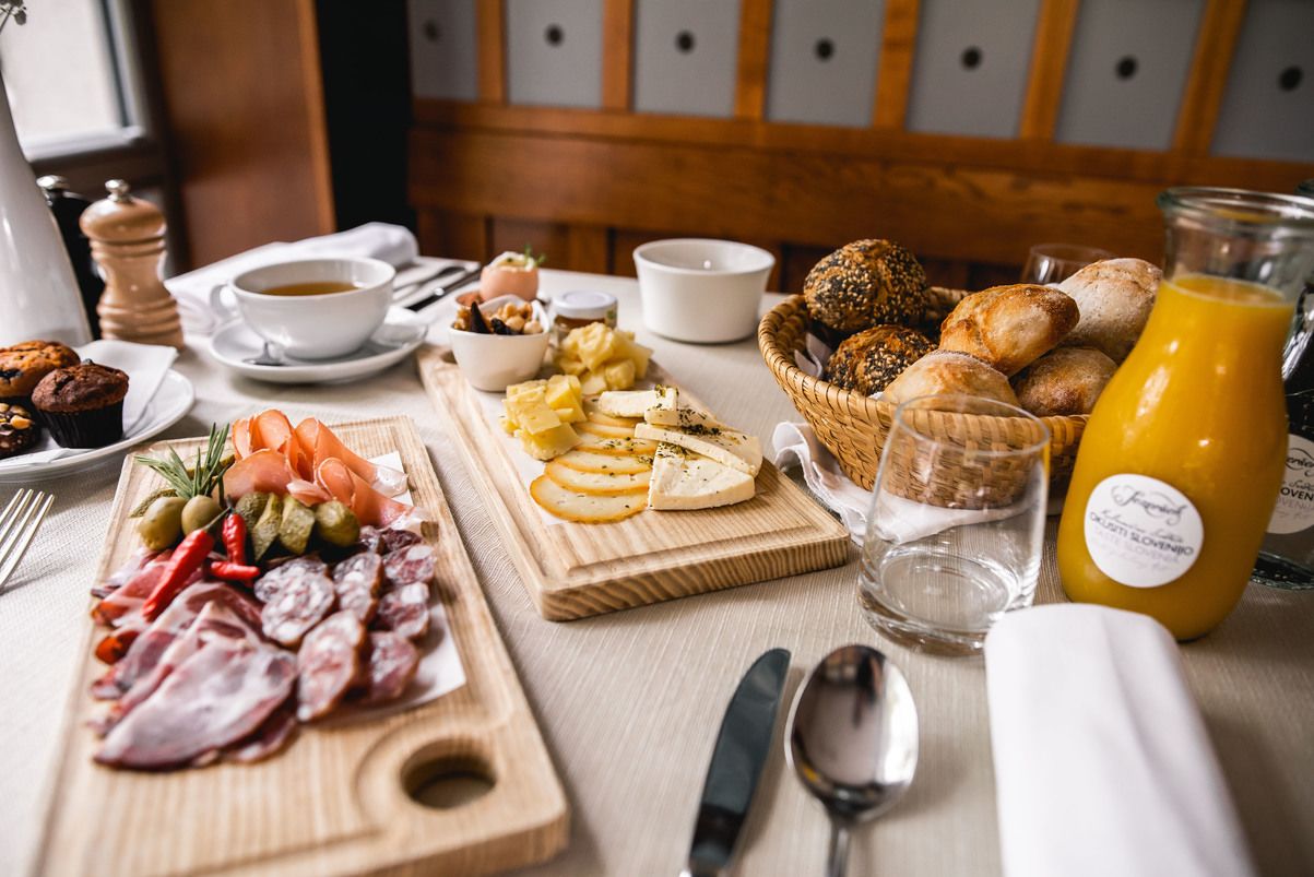 A breakfast buffet with various cheeses, meats, bread, and a glass of orange juice.
