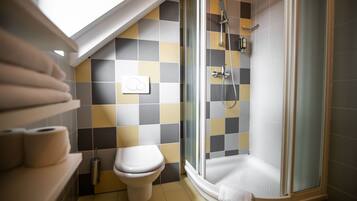 Ein Badezimmer mit Toilette, Dusche und Wand mit Schachbrettfliesen.