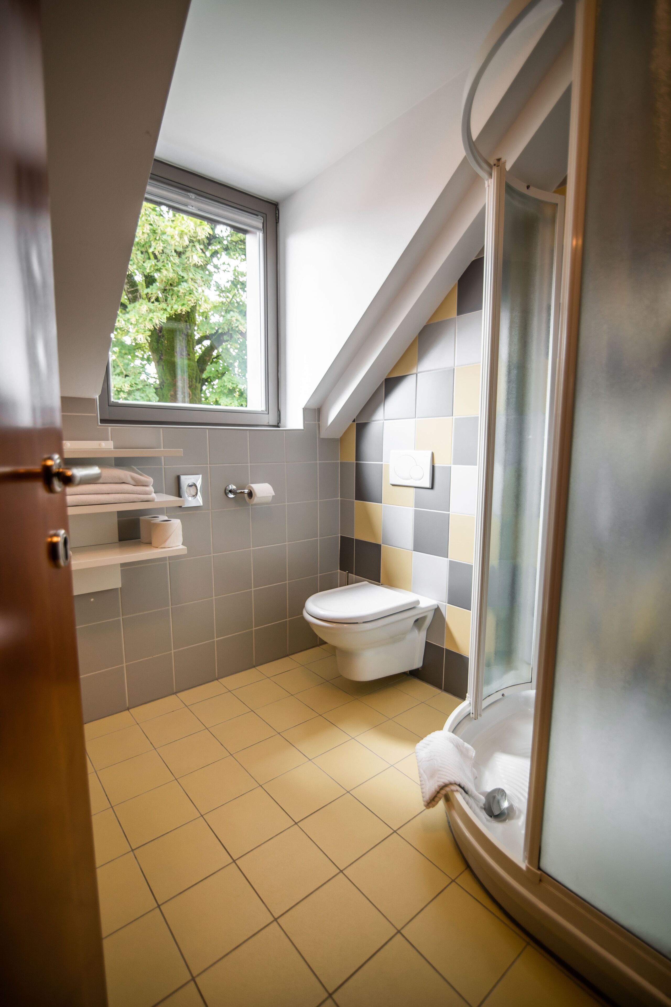 Een moderne badkamer met toilet, douche en een raam dat natuurlijk licht biedt.