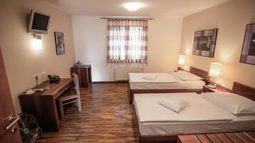 A hotel room with two beds, a desk with a chair, a television, and a window with curtains.